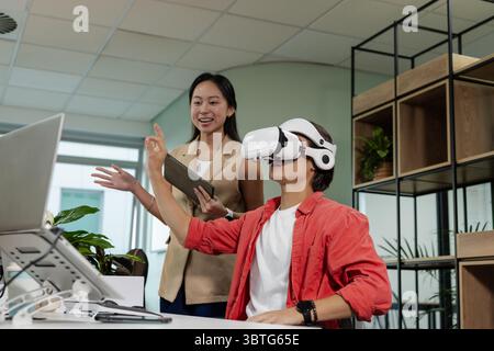 Diverse coworkers testing virtual reality headset using digital tablet at modern office desk Stock Photo