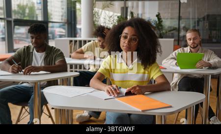 Class lesson in school university college lecture classmates sitting in classroom African American woman girl student female ask teacher problem Stock Photo