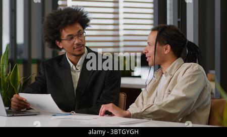 Two multiracial business men African American businessmen partners diverse colleagues males discuss financial data analyzing documents marketing Stock Photo