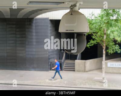 A Hikvision surveillance CCTV camera, produced by the Chinese partly state-owned enterprise, monitors pedestrian activity in the City of London, UK, highlighting the integration of international security technologies in British urban areas Stock Photo