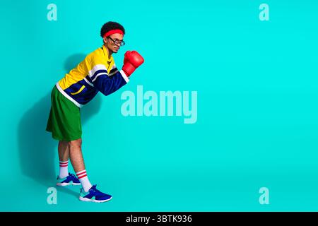 Funny sporty man in retro attire with boxing gloves poses confidently against bright turquoise background Stock Photo