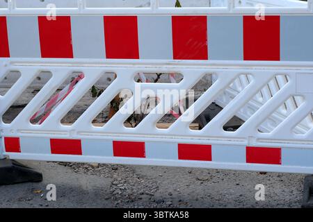 Warning fence for a broken section of the road, plastic white and red fence, city photography in summer on a sunny day close-up Stock Photo