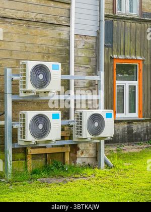Modern air-to-air heat pump systems installed on the exterior of a weathered wooden house, showcasing sustainable climate control solutions Stock Photo