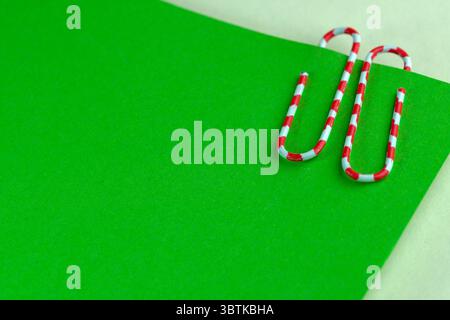 Red paperclip on green blank sheets, stationery art background, macro Stock Photo
