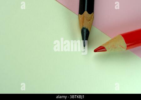 Small green and red pencils lie on sheets of colored paper Stock Photo