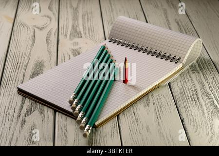 Opened blank notepad with checkered loose-leaf paper with colored pencils in twilight light stationery educational background Stock Photo