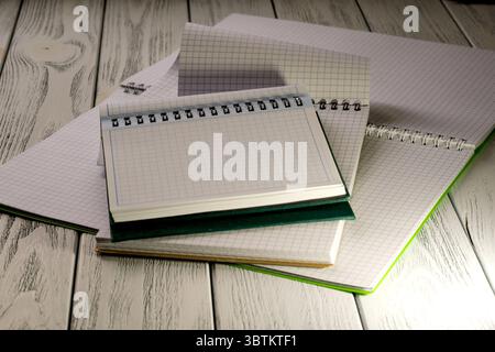 Opened blank notebooks with checkered tear-off leaves on a wooden table in the twilight light stationery educational background Stock Photo
