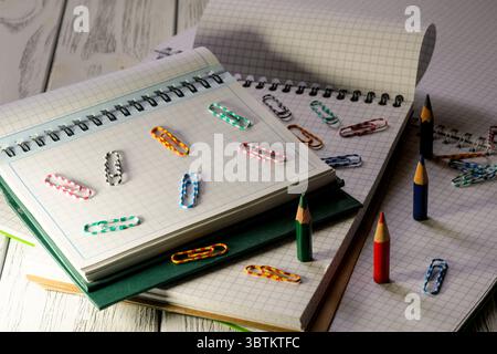 Opened blank notepads with checkered loose-leaf papers with pencils and paper clips in twilight light stationery educational background Stock Photo