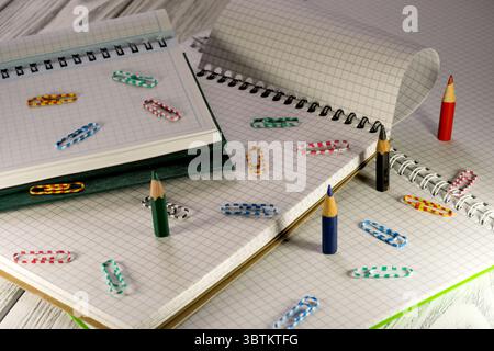 Opened blank notepads with checkered loose-leaf papers with pencils and paper clips in twilight light stationery educational background Stock Photo