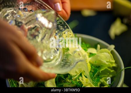 A vivid macro shot capturing a woman slicing a fresh lemon and squeezing its juice over a colorful salad, highlighting citrus texture and freshness in Stock Photo