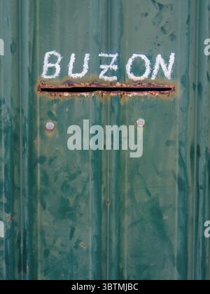A rustic mailbox consisting in a slot on the metallic door, and written in white paint over it 'mailbox', in Spanish. In a house in the town of Sora Stock Photo