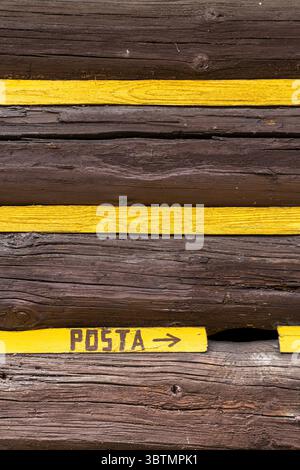 Yellow arrow pointing to the post office painted on a traditional wooden wall in Osturna, Slovakia Stock Photo