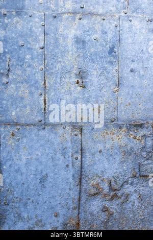 Rusty metal plates showing signs of aging and wear, creating a textured backdrop with rivets and paint remnants Stock Photo
