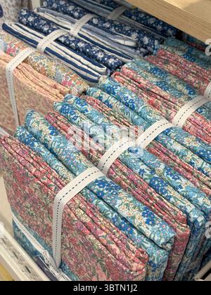 Bundles of Floral Fabrics on Shelf, Quilting and Sewing Essentials in Pastel Harmony Stock Photo