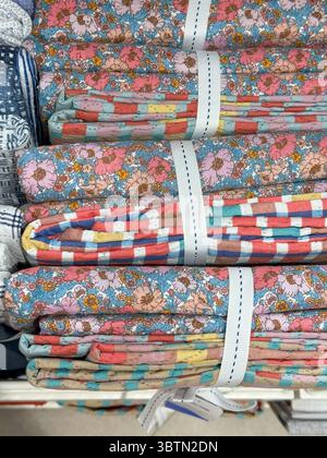 Bundles of Floral Fabrics on Shelf, Quilting and Sewing Essentials in Pastel Harmony Stock Photo