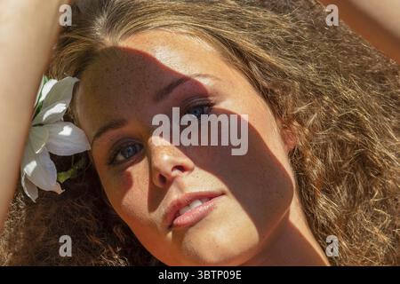 Close up portrait of beautiful young woman shading eyes in sunlight Stock Photo