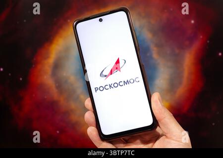 BOGOTA, COLOMBIA - JULY 14 OF 2025 A male hand holding a smartphone with Roscosmos logo in russian with blurred nebula at background Stock Photo