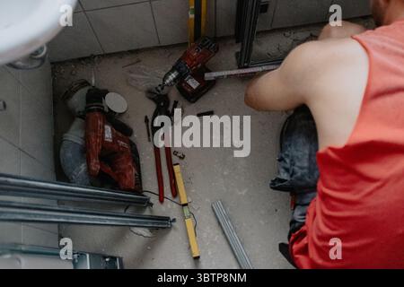 A male craftsman installing a cantilevered wall made of steel profiles using the appropriate tools. Stock Photo