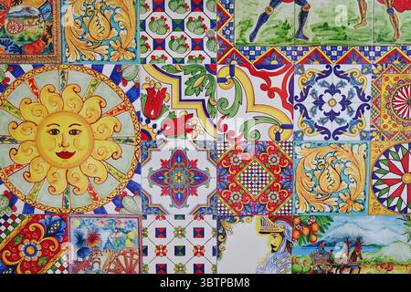 Colorful Sicilian ceramic tiles with traditional motifs including sun face, knights, fruits, floral ornaments, and geometric patterns. Stock Photo