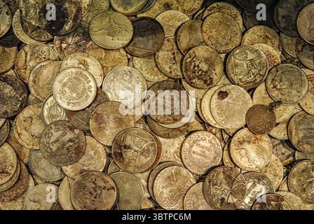 Old silver and bronze coins from various countries in a close-up view. A mix of vintage currency with signs of age and oxidation. Stock Photo