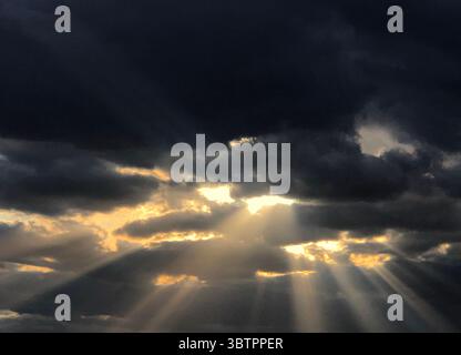 Rays of Sunlight Shining Through The Clouds of a Storm Stock Photo