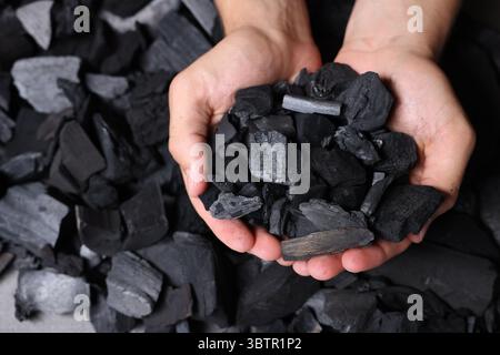 Man with black coals over pile, top view Stock Photo