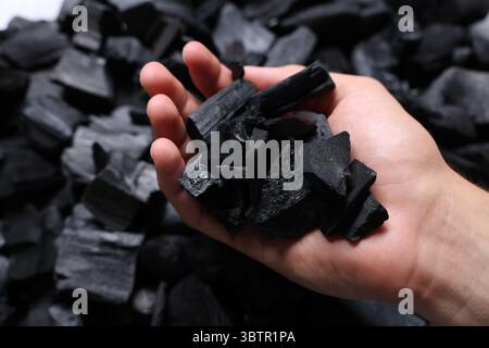 Man with black coals over pile, closeup Stock Photo