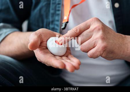 Hand pushing panic button on emergency equipment for elderly people Stock Photo