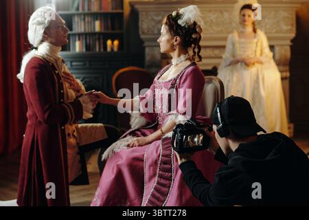 Man in historical Baroque costume kneeling and holding hand of Caucasian middle aged woman in ornate Renaissance dress Stock Photo