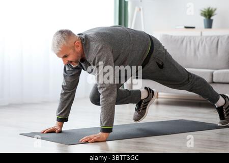Athletic bearded senior man doing exercises at home Stock Photo