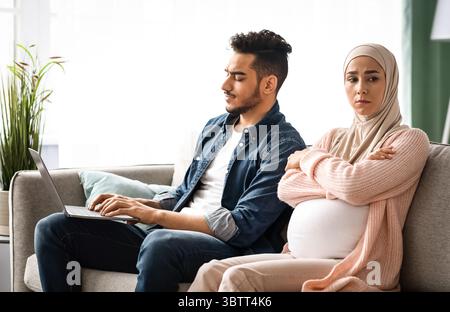 Bored Pregnant Muslim Lady Offended To Her Husband Busy With Laptop Stock Photo