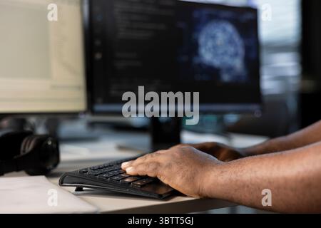 Engineer typing on keyboard, doing data center automation using AI and machine learning tools. Close up of IT expert integrating artificial intelligence driven automation in server room operations Stock Photo