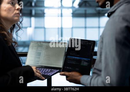 Programmers in data center using devices, executing security patches, verifying firewall configurations, performing vulnerability scans, tracking suspicious activity, ensuring data protection Stock Photo