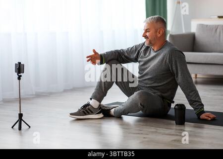 Handsome senior man fitness coach broadcasting from home Stock Photo
