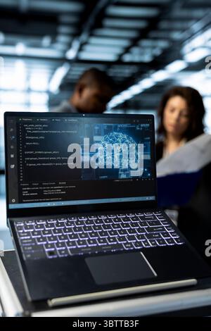 Focus on laptop used by teamworking data center computer scientists in blurry background using artificial intelligence neural networks to do computing processes, close up shot Stock Photo