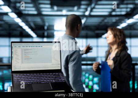 Focus on laptop in data center used by software developers refining server virtualization strategies. Close up of notebook in server room used by professional programmers Stock Photo