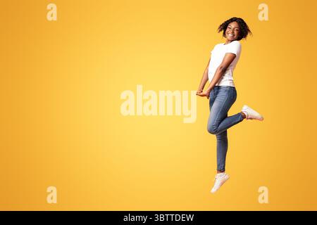 Happy young black woman posing on orange Stock Photo