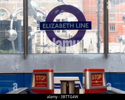 Elizabeth Line Roundel Displayed on Glass Entrance with Emergency Stop Buttons Visible at Top of Escalator in London Tube Station UK Stock Photo