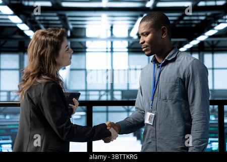 Manager meeting with computer scientist in data center, coming to inspect servers. Supervisor doing handshake with system administrator in server room, overseeing supercomputers Stock Photo
