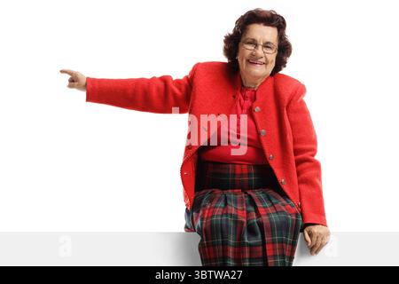 Elderly woman sitting on a panel and pointing to the side isolated on white background Stock Photo