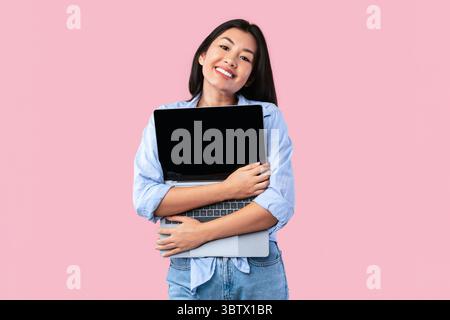 Excited asian woman hugging personal computer at studio Stock Photo