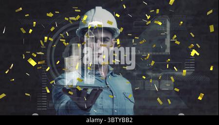 Displaying holographic skyscrapers, helmeted engineer using interface in studio, with confetti Stock Photo