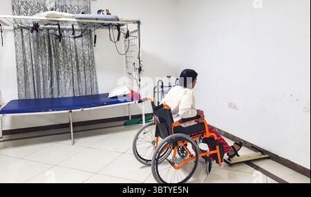 wheelchair patient performing paralyzed foot recovery exercise in physiotherapy session at indoor Stock Photo