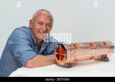 Serge Mathot with the first of four modules that will make up the miniature accelerator built and designed at CERN (European Organization for Nuclear Research) near Geneva, Switzerland. At just two metres long, it has been developed to be used in hospitals for medical imaging and the treatment of cancer The HF-RFQ (High Frequency Radio Frequency Quadrupole) is the first compact accelerator built and designed at CERN. Stock Photo