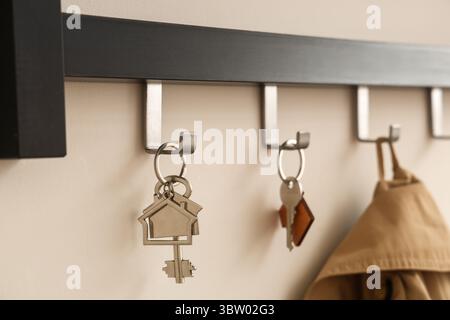 Rack with keys from house on light wall, closeup Stock Photo