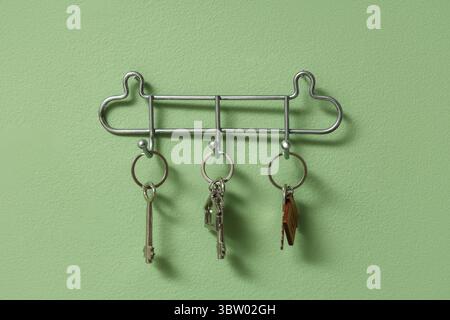 Rack with keys from house on green wall Stock Photo