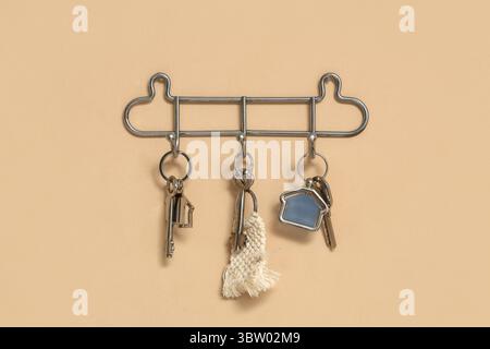 Rack with keys from house on beige wall Stock Photo