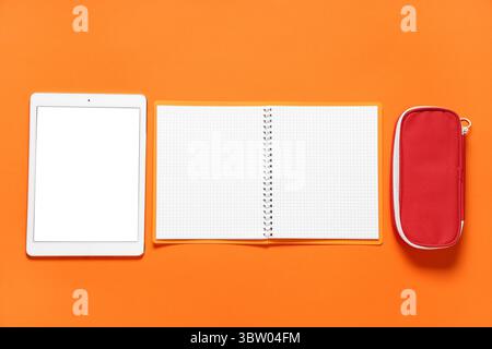 Composition with modern tablet computer and school supplies on orange background Stock Photo