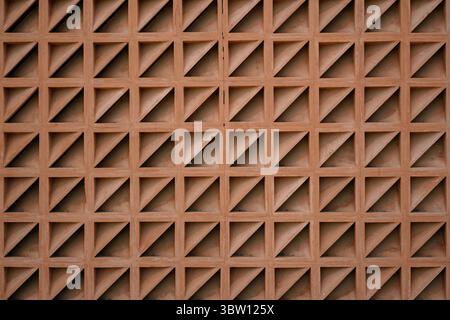 Terracotta breeze block wall with a repeating triangular pattern. Abstract geometric background creating a sense of texture and rhythm. Stock Photo