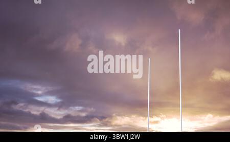 Flat design is showing slim white poles rising against sunset sky with golden lavender clouds Stock Photo